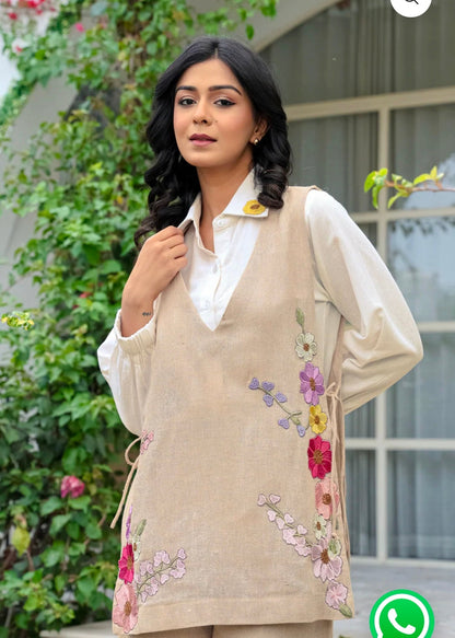 Woman wearing a beige embroidered outfit with a blurred background